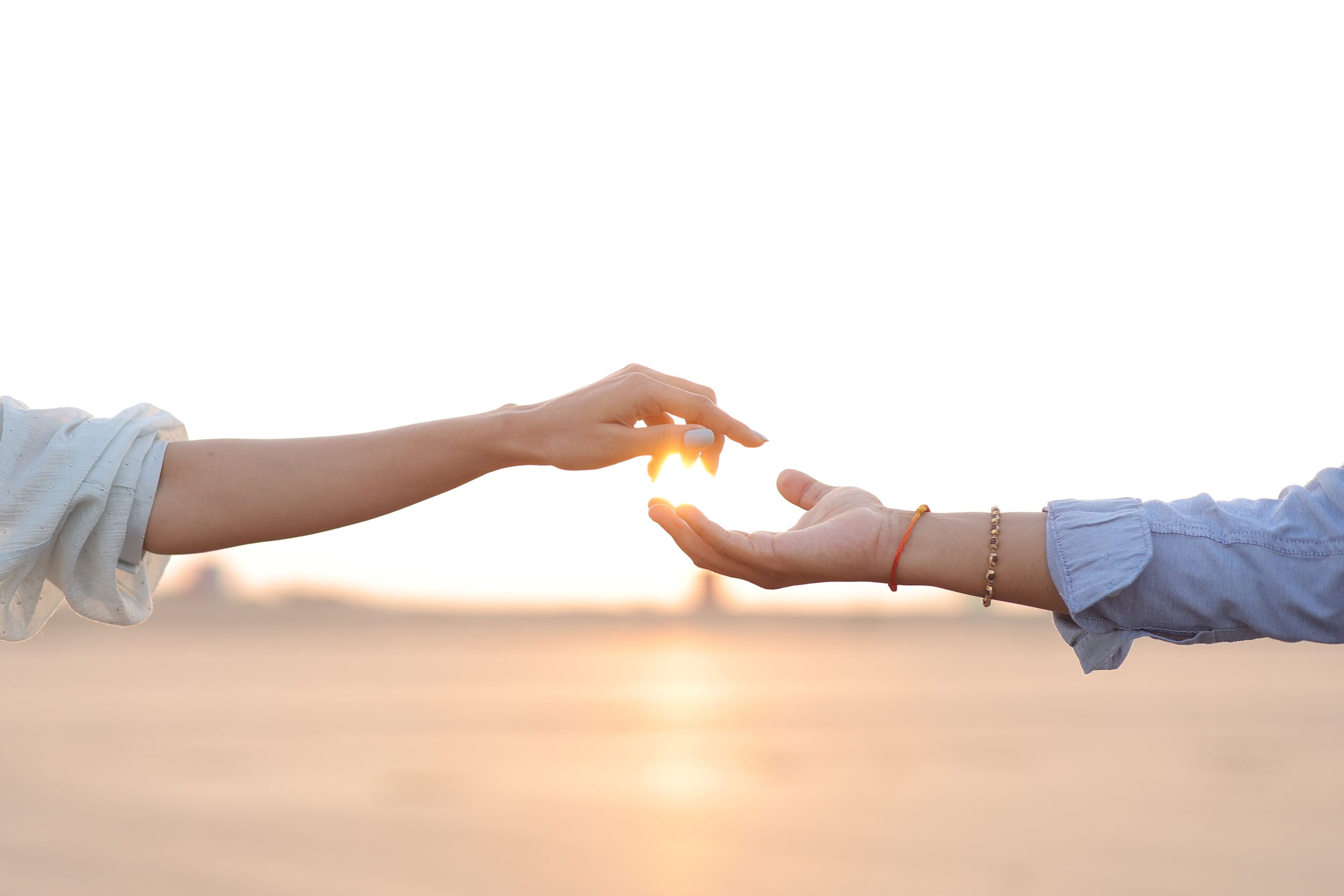 pexels-ds-babariya-756428940-31564184 Two people reaching towards each other with outstretched hands, fingertips almost touching, against a bright, soft-focus sunset background—a moment of connection reminiscent of the support found in Campral’s journey toward hope and renewal.